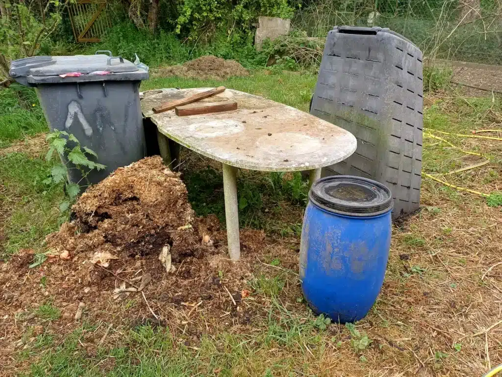 Ouverture d'un composteur en plastique pour extraire la terre grasse destinée à la plantation des courgettes au printemps.